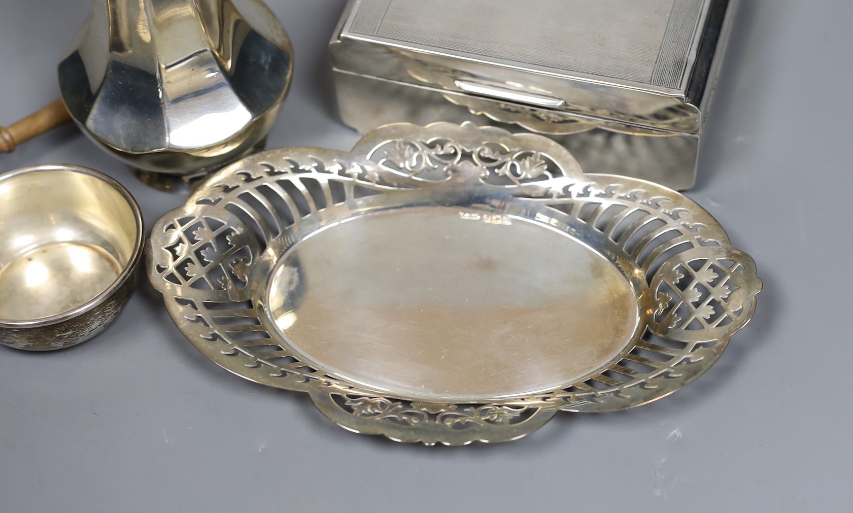 A George V engine turned silver mounted cigarette box, a similar sugar caster and later silver tea strainer and small dish.